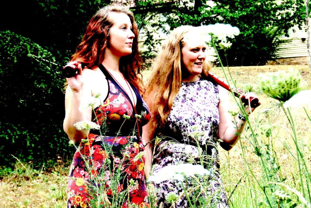 Two women in a field holding recorders